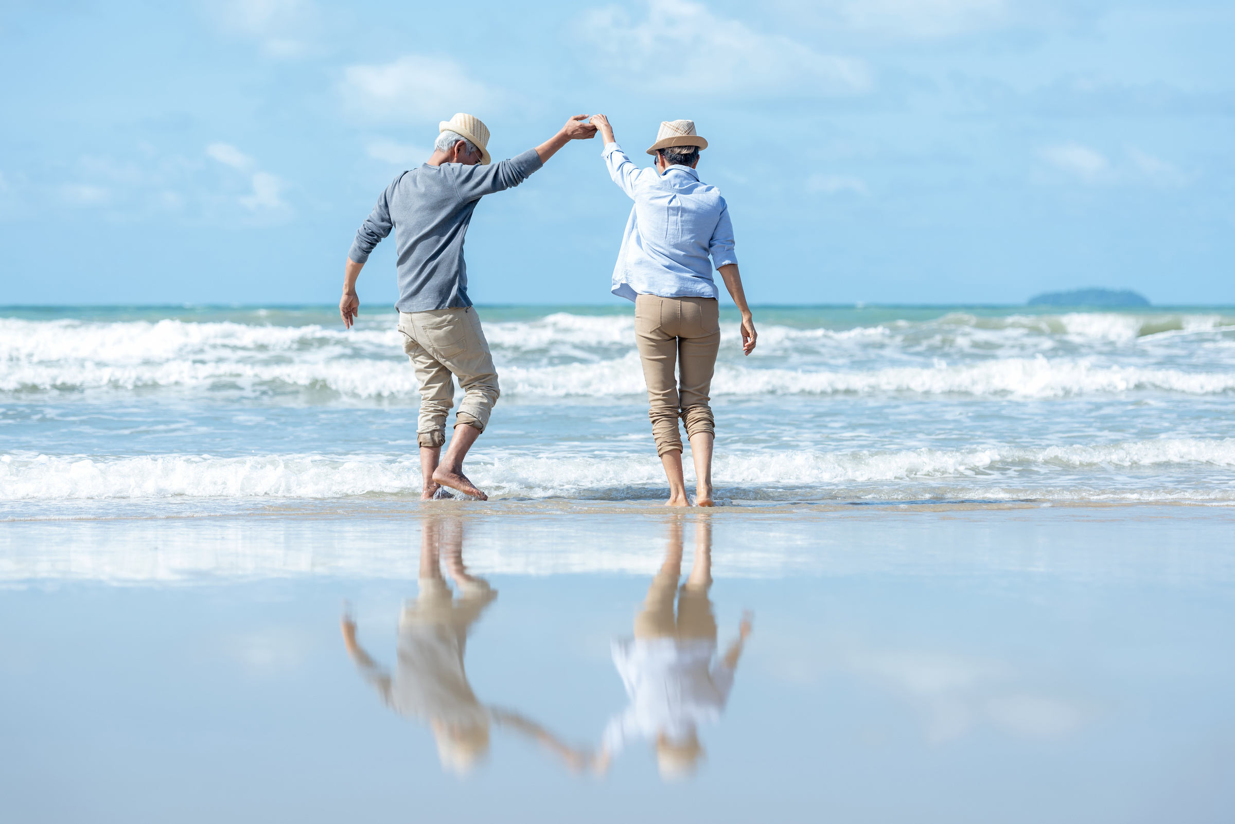 Retired couple dancing on the beach together at the water's edge